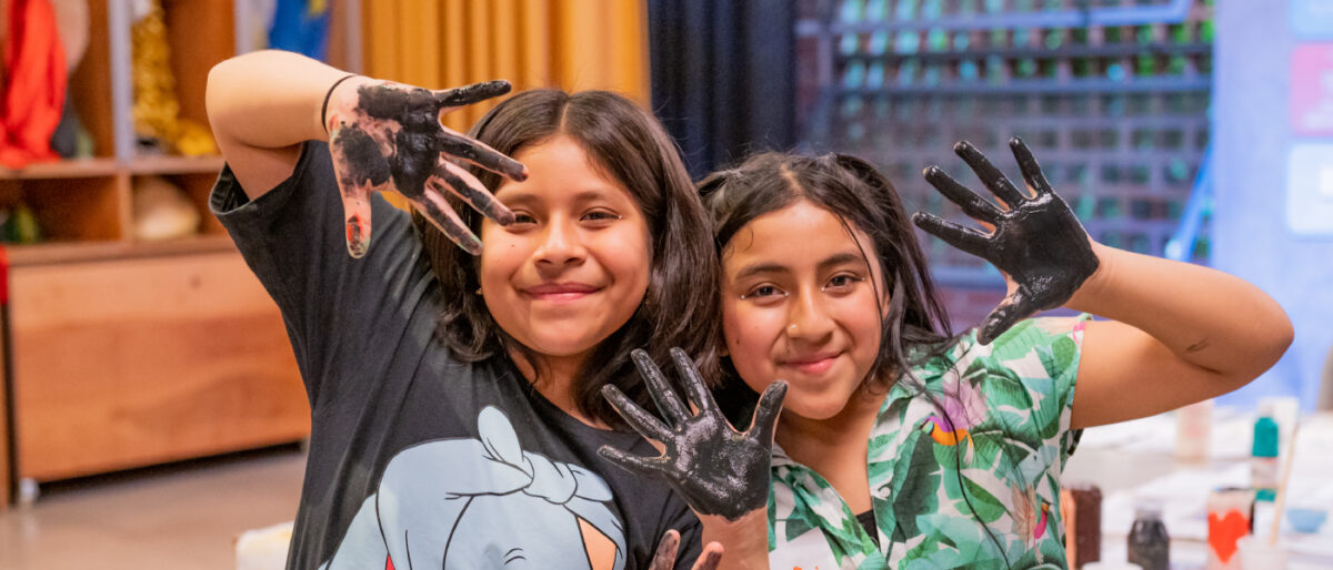 Vemos un par de niñas con sus manos pintadas, pero felices y posando a la cámara mostrando las palmas de sus manos. Esta foto sirve como portada para hablar de la importancia del juego como actividad esencial para el desarrollo de niñas, niños y jóvenes.