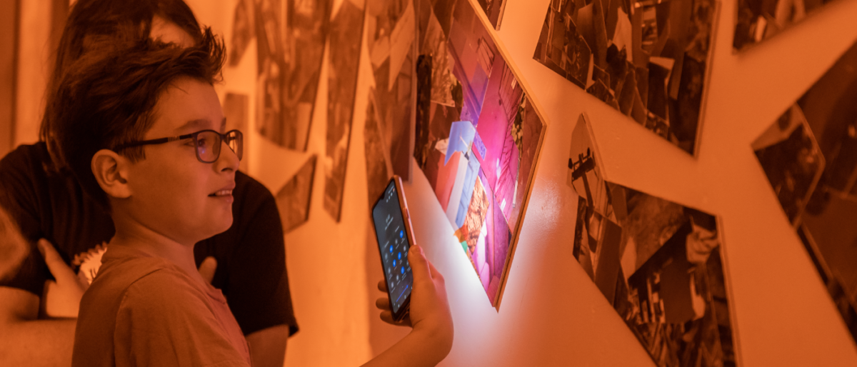 Niños mirando fotografías en una pared, en un cuarto oscuro. Portada del artículo sobre Kavafis, Jobs y la innovación.